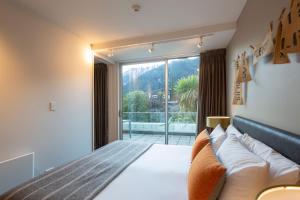 Un dormitorio con una cama y una ventana grande. en Kent Street Apartments - Element Escapes, en Queenstown