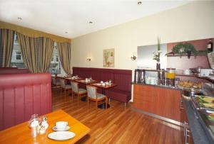 a restaurant with a long table and a kitchen at Hotel Terminus am Hauptbahnhof & ZOB in Hamburg
