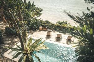 a swimming pool next to the ocean with chairs at Frangipani El Nido in El Nido