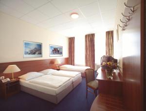 a hotel room with two beds and a desk at Hotel Terminus am Hauptbahnhof & ZOB in Hamburg