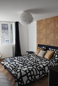 a bedroom with a bed with a black and white comforter at LE SELECT DE BROU in Bourg-en-Bresse