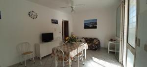 uma sala de jantar com mesa e cadeiras e uma televisão em Il Faro di Anna em Leuca
