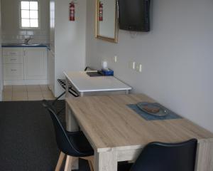 cocina con mesa de madera y 2 sillas en Ashmont Motel and Apartments en Port Fairy