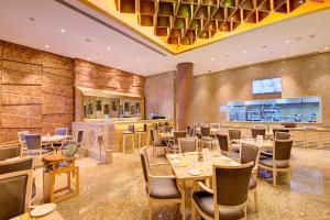 um restaurante com mesas e cadeiras e um bar em Niranta Transit Hotel Terminal 2 Arrivals/Landside em Mumbai