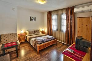 a bedroom with a bed and a chair and a television at Keremidchieva Kushta Guest House in Sandanski