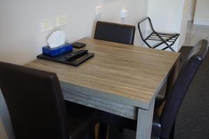 uma mesa de madeira com cadeiras e uma caixa de tecidos em Ashmont Motel and Apartments em Port Fairy