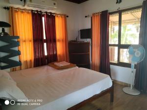 een slaapkamer met een bed met oranje gordijnen en een ventilator bij SAGAR BEACH VILLAS in Cherai Beach