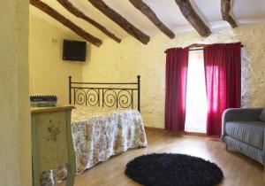 1 dormitorio con cama con cortinas rojas y sofá en Agroturismo La Artezuela, en Letur