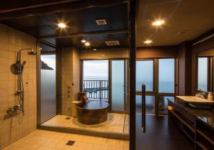 a bathroom with a tub and a view of the ocean at Meijikan in Izu