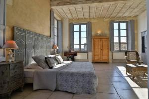 a bedroom with a large bed in a room with windows at Le Posterlon in Caumont-sur-Durance