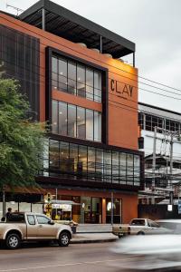 a building with a car parked in front of it at Clay Hotel Udonthani in Udon Thani