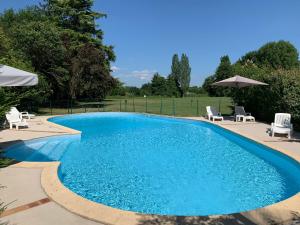 una gran piscina con sillas y sombrillas en Les Rives du Plantié, en Le Temple-sur-Lot