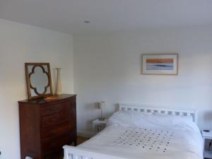 Littlemead - Newly renovated private studio near Glastonbury في غلاستونبري: غرفة نوم بسرير ابيض وخزانة خشبية