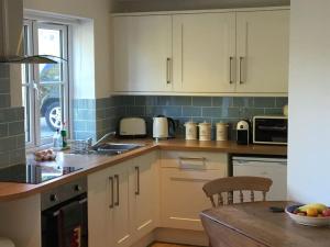 a kitchen with white cabinets and a wooden table at Littlemead - Newly renovated private studio near Glastonbury in Glastonbury