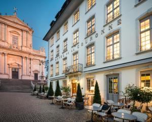 ein großes weißes Gebäude mit Tischen und Stühlen im Innenhof in der Unterkunft Boutique Hotel La Couronne in Solothurn