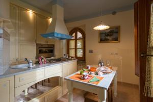 cocina con armarios blancos, fregadero y mesa en San Bartolomeo Suite, en Castel Rigone