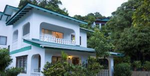 a white house with a balcony and trees at Le Manglier in Pointe Larue