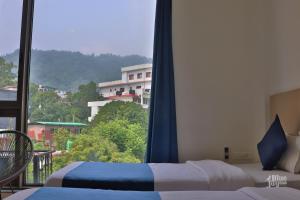 a bedroom with two beds and a large window at Blue Jay Hostel Rishikesh in Rishīkesh