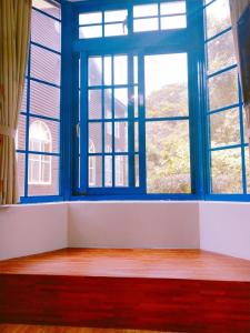 Habitación vacía con 2 ventanas y suelo de madera. en Star Coffee & Homestay, en Nanzhuang