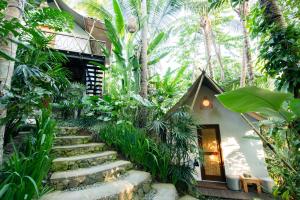 ogród ze schodami prowadzącymi do domu z palmami w obiekcie Ubud Tropical w mieście Ubud
