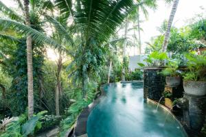 a swimming pool in a resort with palm trees at Ubud Tropical in Ubud