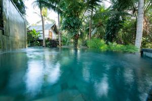 uma piscina de água azul em frente a uma casa em Ubud Tropical em Ubud