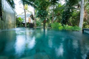 a pool of blue water in front of a house at Ubud Tropical in Ubud