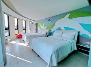 a bedroom with two beds and a dolphin mural at Shell Sand Homestay in Magong