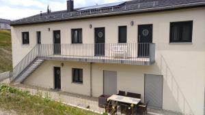 Un edificio blanco con puertas negras y un balcón. en Ferienwohnungen direkt am See, en Mücheln