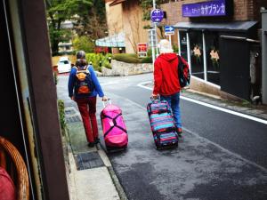 箱根的住宿－隱居旅館，两个人带着行李沿着街道走