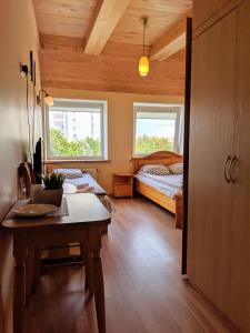 sypialnia z łóżkiem i stołem oraz 2 oknami w obiekcie Guest House Kamara w Poniewieżu