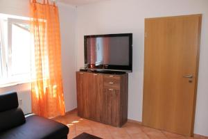 Una sala de estar con un televisor de pantalla plana sobre un mueble de madera. en Ferienwohnung Jasmin in Schönau bei Heidelberg FEWO 2, en Schönau