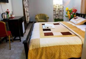 a bedroom with a large bed with a desk and chairs at Comfort Hotel Entebbe in Lyamutundwe +35 photos