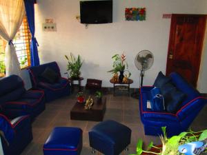 uma sala de estar com sofás azuis e uma televisão de ecrã plano em Hotel Huito em Leticia