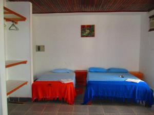 a bedroom with two beds with blue and red sheets at Hotel Huito in Leticia