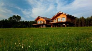 a wooden house on top of a green field at Ami Residence in Druskininkai