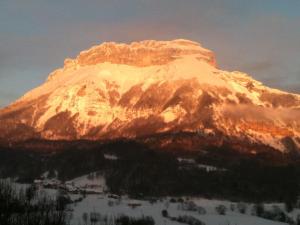 una montaña cubierta de nieve con el sol brillando sobre ella en Bar Hotel Restaurant le Margeriaz, en Les Déserts