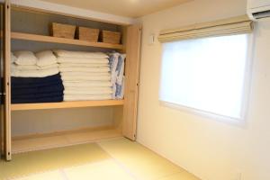 einen begehbaren Kleiderschrank mit Handtüchern und einem Fenster in der Unterkunft ペンション 玉ぃ家〜 in Nakijin