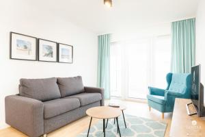 un soggiorno con divano e sedia di Jantar Apartamenty - DELUXE 38 Bałtycka 6 a Kołobrzeg