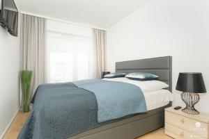 biała sypialnia z łóżkiem i oknem w obiekcie Jantar Apartamenty - DELUXE 38 Bałtycka 6 w Kołobrzegu