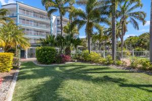 a large building with palm trees in front of a yard at White Crest Apartments in Hervey Bay