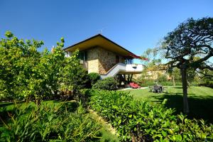 una casa con un giardino verde con un albero di Il Melograno - San Quirico d'Orcia a San Quirico dʼOrcia