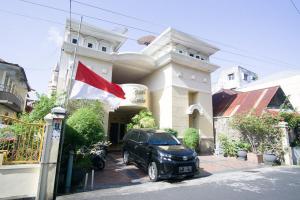 RedDoorz near Pantai Falajawa Ternate في تيرنيت: سيارة متوقفة أمام مبنى عليه علم