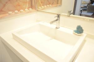 lavabo blanco en el baño con espejo en ペンション 玉ぃ家〜 en Nakijin