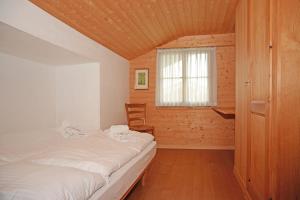 um pequeno quarto com uma cama e uma janela em Traditionelles Chalet Schärmtanne em Aeschi