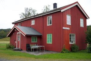 un granero rojo con una mesa delante en Kirkvollen pilegrimsgård en Tydal