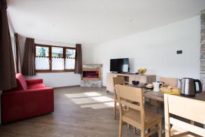 een woonkamer met een tafel en een rode stoel bij Steinbock B&B - Apartaments in Livigno