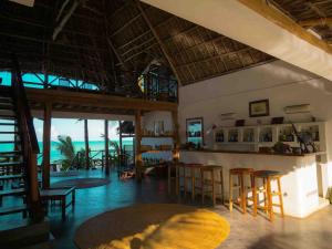 a room with chairs and a bar with the ocean at Hekaya Zanzibar in Pingwe