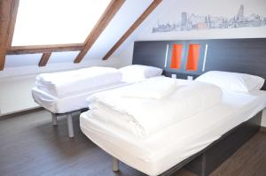 duas camas em um quarto com lençóis brancos em easyHotel Zürich West em Zurique