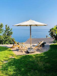 un patio con sombrilla, sillas y el océano en Casa Isabella, en Malfa